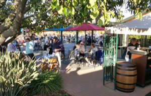 Wine tasting event A wine tasting event, showing people sitting under colorful umbrellas near wine barrels